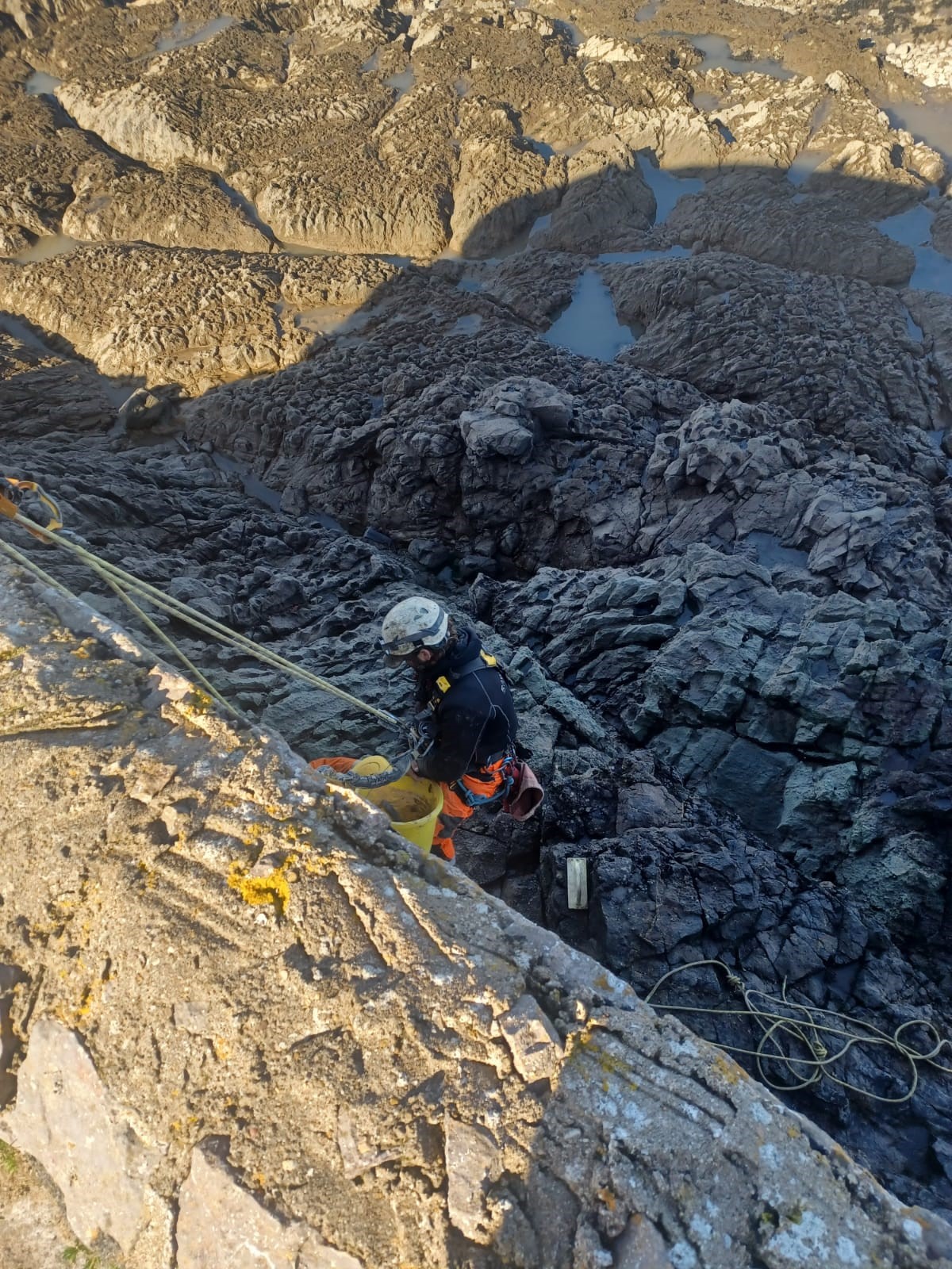 A construction worker abseiling to carry out repairs and repointing to the sea walls